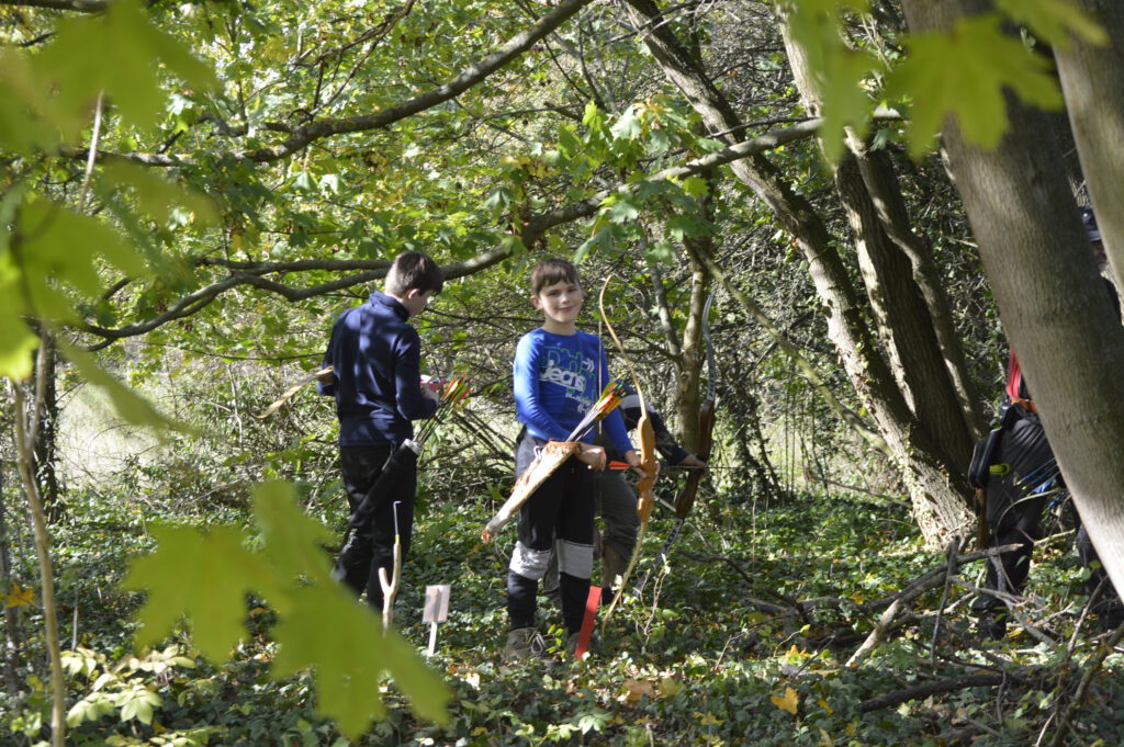 Zwei Jugendlich beim Bogenschießen im Wald